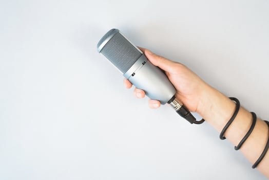 Male hand holding studio microphone, top view, light background. Cable is wrapped around the arm. Blogging, sound recording, podcast concept. photo