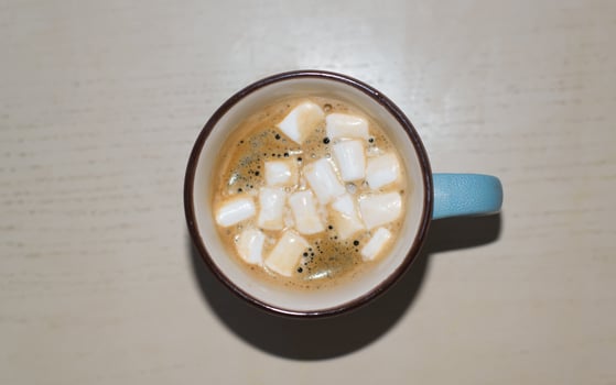 Mug of coffee with marshmallows standing on the table indoors, top view photo