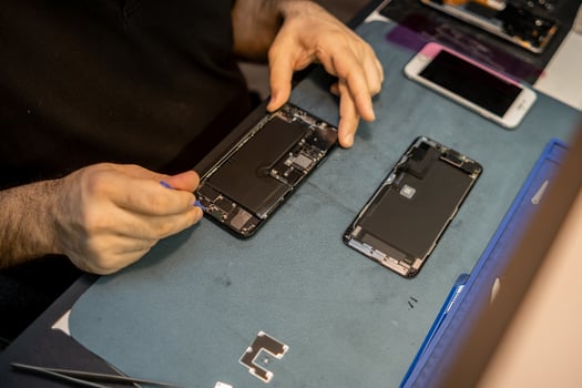 Expert Phone Technician Repairs Smartphone Components in a Dedicated Workspace, Showcasing Precision and Skill in Phone Repair on a Recent Afternoon photo