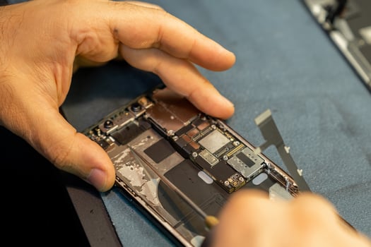Expert Phone Repair Technician Replacing Parts Inside a Smartphone on a Workbench in a Well-Lit Workshop photo