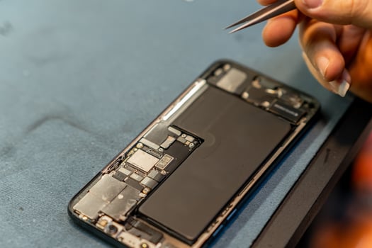 Skilled Technician Performing Phone Repair With Precision Tools in a Workshop Setting During Daylight Hours photo