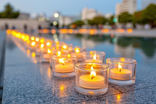 Row of illuminated candles placed on a reflective surface, creating a serene atmosphere during a memorial event, symbolizing remembrance and peace in a tranquil setting photo