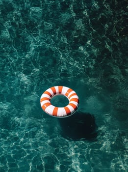 Lifesaver Ring Floating in Clear Swimming Pool Water on a Sunny Day photo