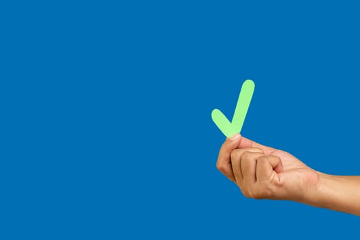 Hand holding a green check mark symbol against a blue background. photo