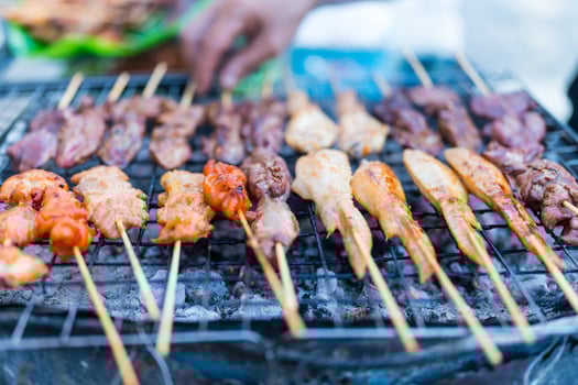 Street food vendor preparing Thai grilled street food with meat, chicken on sticks. photo