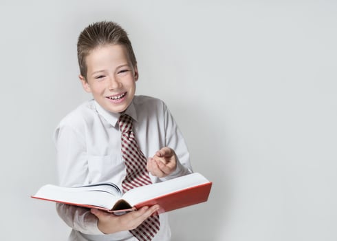 Laughing schoolboy reads a red book horizontal background photo