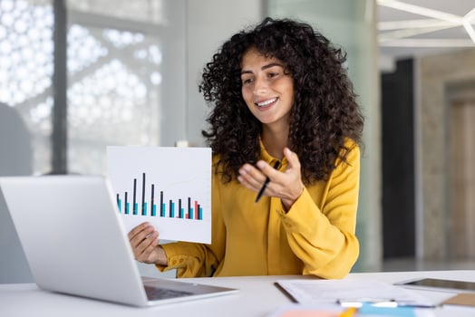 Businesswoman is presenting a financial report during an online conference in a bright office space, using graphs for clarity photo