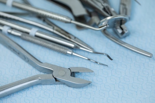 Close-up of various stainless steel dental instruments on a blue surface. photo