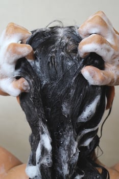 A woman is taking a shower and washing her hair in the bat photo