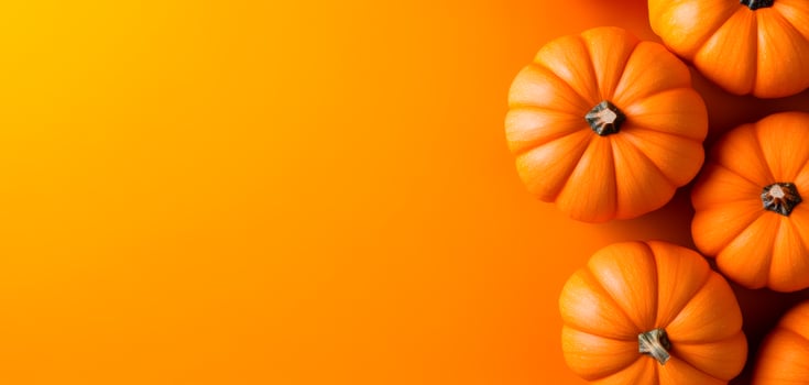 Orange pumpkins on bright bg. Small, round pumpkins are arranged on an orange background, creating a cheerful autumn atmosphere. photo