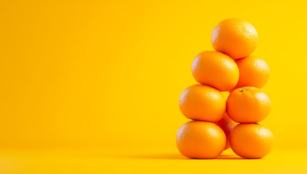 Oranges on yellow background. A vibrant arrangement of stacked oranges creates a cheerful display against a bright yellow backdrop. photo