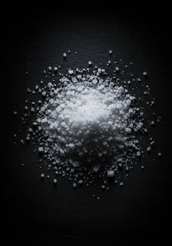 Pile of coarse salt crystals on a black surface. photo