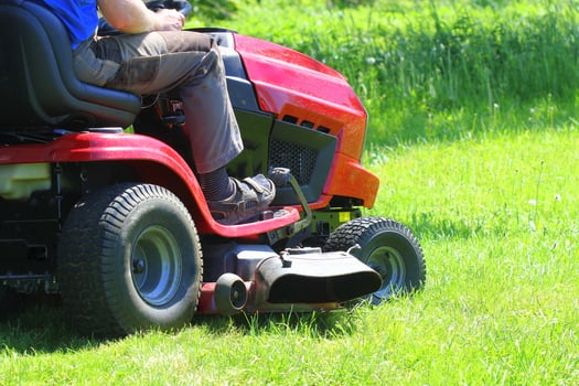 Gardener driving a riding lawn mower in a garden photo