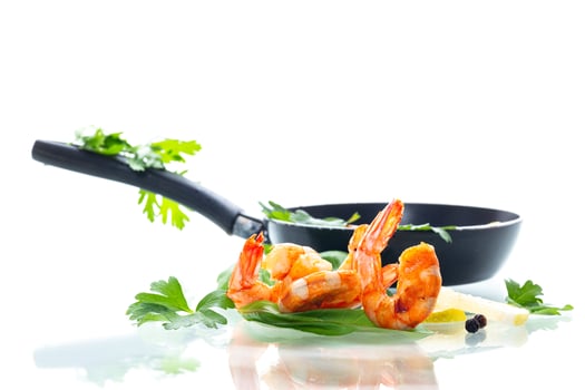 Golden fried shrimps with spices and fresh lemon in a frying pan isolated on white photo