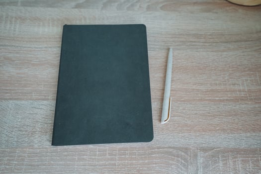On a smooth wooden table rests a beautifully designed notebook and polished pen, creating an inviting scene perfect for jotting down notes and inspiring thoughts on a productive day photo