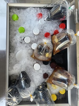 Bottles of soda and juice chilling on ice with colorful caps and plastic bags filled with beverages, creating refreshing display for party or gathering. ice keeps drinks cold and ready to serve photo