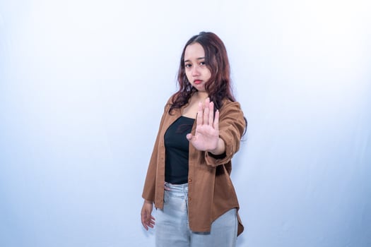 Indonesian Asian woman wearing brown shirt giving stop signal by raising one hand photo