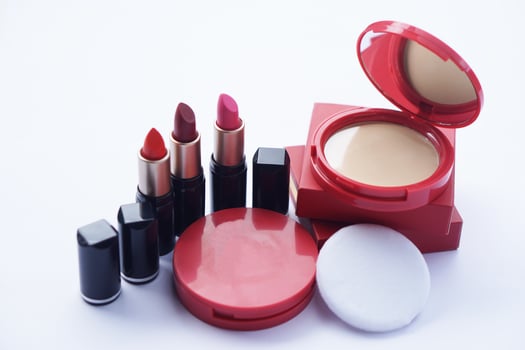 Elegant red compact foudation face powder matching lipstick in black tube, displayed with soft puff and built-in mirror. Concept for glowing skin and bold, confident lips. Ideal for modern women. photo