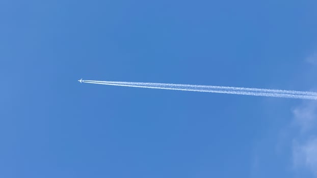 A solitary jet pierces the azure sky with whispering contrail secrets, echoing World Aviation Day and Sky Awareness Week photo