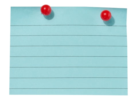 A sheet of blue lined paper attached with two red pushpins on an isolated background photo