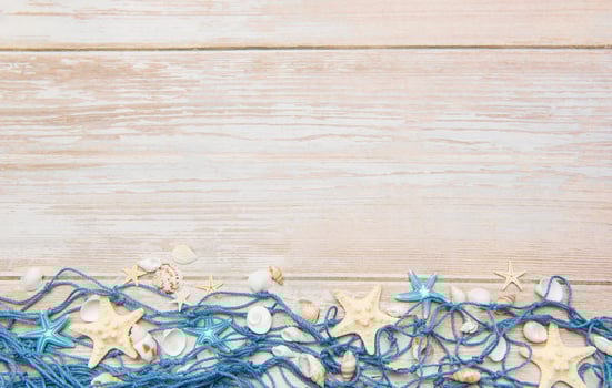 Fishing net with starfishes and seashells creating summer holiday border on wooden planks photo