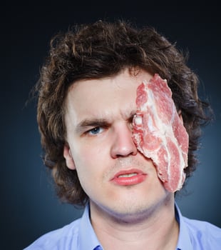 Man with raw steak on face for injury treatment humorous portrait concept health home remedy pain relief photo