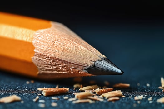 Sharpened pencil resting on dark surface with shavings photo