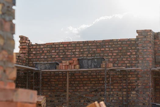 Construction workers are busy stacking bricks on site to build a sturdy wall while sunlight illuminates the surroundings photo
