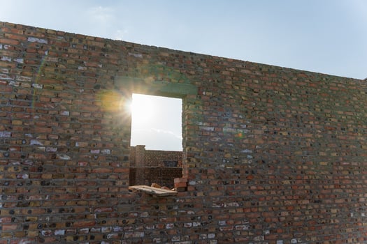 Bright sunlight shines through an unfinished window opening in a newly constructed brick wall on a building site photo