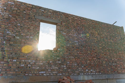 Bright sunlight shines through an unfinished window in a brick wall, indicating progress in a construction project during morning hours photo
