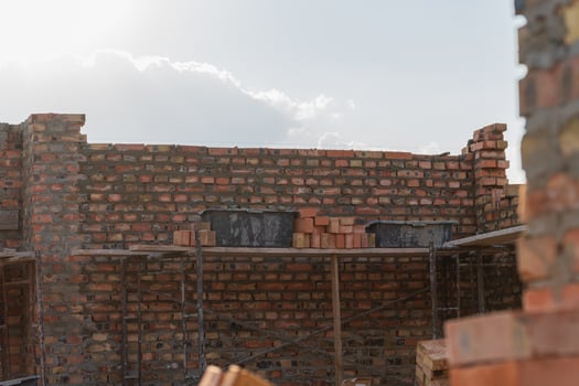 Brick walls under construction in a building renovation project, surrounded by scaffolding, reflecting afternoon sunlight photo