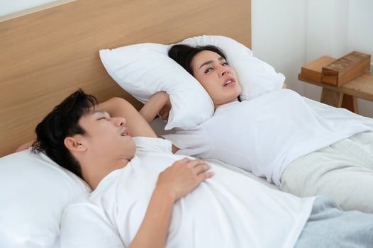 Couple Sleeping in Bed With One Partner Snoring Loudly in a Bright Room photo