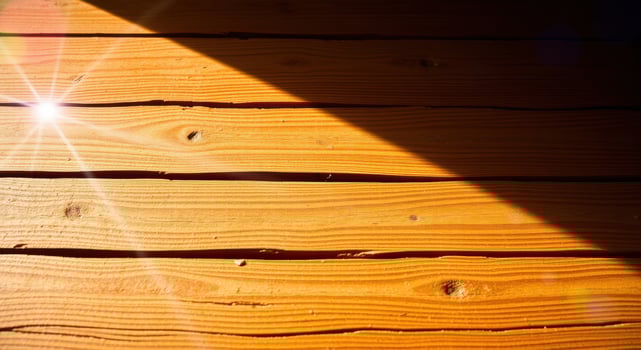 Sunlight hitting wooden boards in a play of light and shadow, creating a warm, inviting textured surface. photo