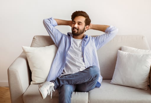 Weekend At Home. Relaxed Arab Guy Leaning Back On Couch With Hands Behind Head, Cheerful Middle Eastern Man Resting On Comfortable Sofa In Cozy Living Room , Enjoying Spending Day Off, Copy Space photo