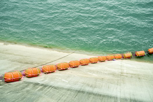 Line of orange debris barrier floating near intake zone of a hydroelectric dam to protect turbine system from vegetation and log blockage during active power generation and water flow control. photo