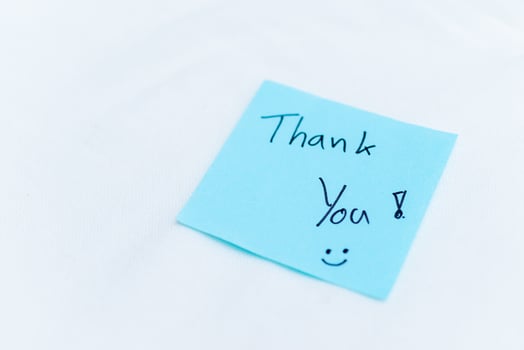 Thank you note on blue sticky pad office setting personal gesture clean environment close-up view concept of appreciation in business photo
