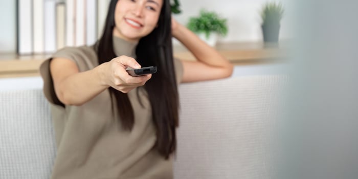 Cheerful woman pointing remote control. Enjoying TV time at home. photo