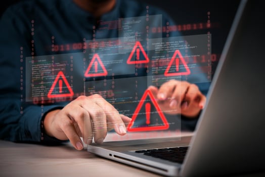 Cyber security and hacking concept - man using laptop with red warning icons on screen photo