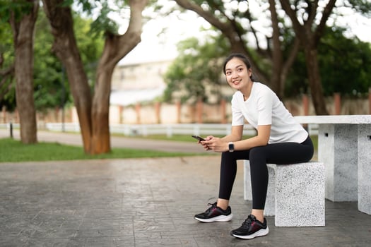 Casual Fitness Break. Young woman sitting on park bench, enjoying a moment of relaxation. photo