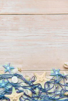 Fishing net with starfish and seashells creating summer holiday border on wooden planks photo