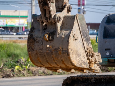 Excavator digging earth construction site urban area machinery action daylight close-up view photo