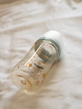 Feeding time for babies transparent baby bottle soft surface lifestyle setting close-up viewpoint photo