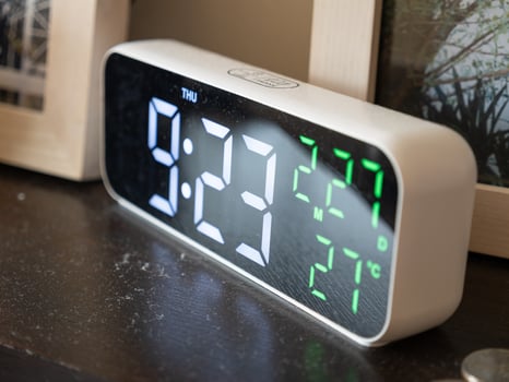 Digital alarm clock displaying time and temperature cozy bedroom setting photo