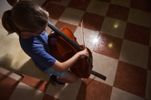 Young Musician Playing the Cello in a Well-Lit Room with Checkered Tiles photo