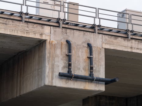 Urban infrastructure elevated industrial pipe installation over concrete bridge photo