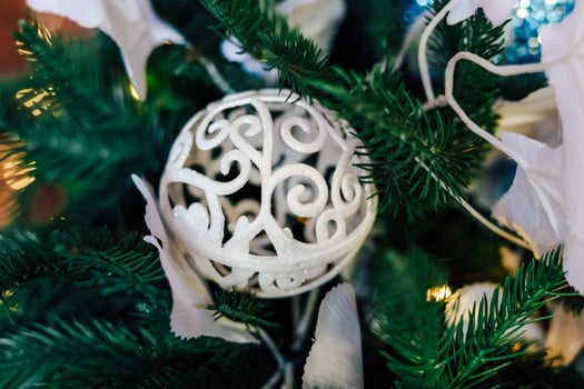 Delicate white ornament nestled among lush green Christmas tree branches photo