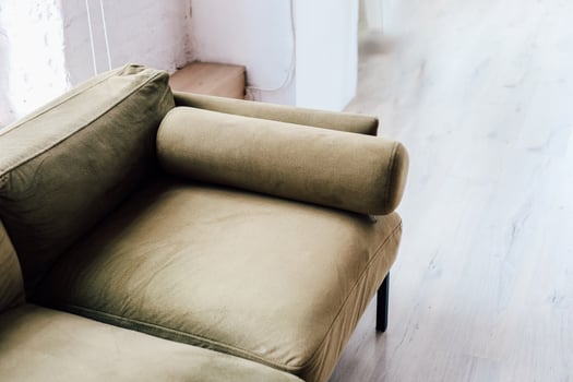 Modern olive green sofa with a unique cylindrical armrest displayed in bright interior space photo