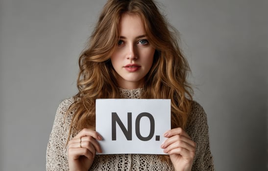 Woman holding sign saying NO in front of her face against a neutral background photo
