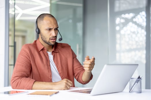 A man with a headset gestures emphatically during a call, expressing surprise and consternation with his facial expression. photo
