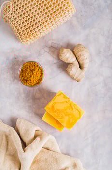 Herbal turmeric soap bars and root on the table top and vertical view photo